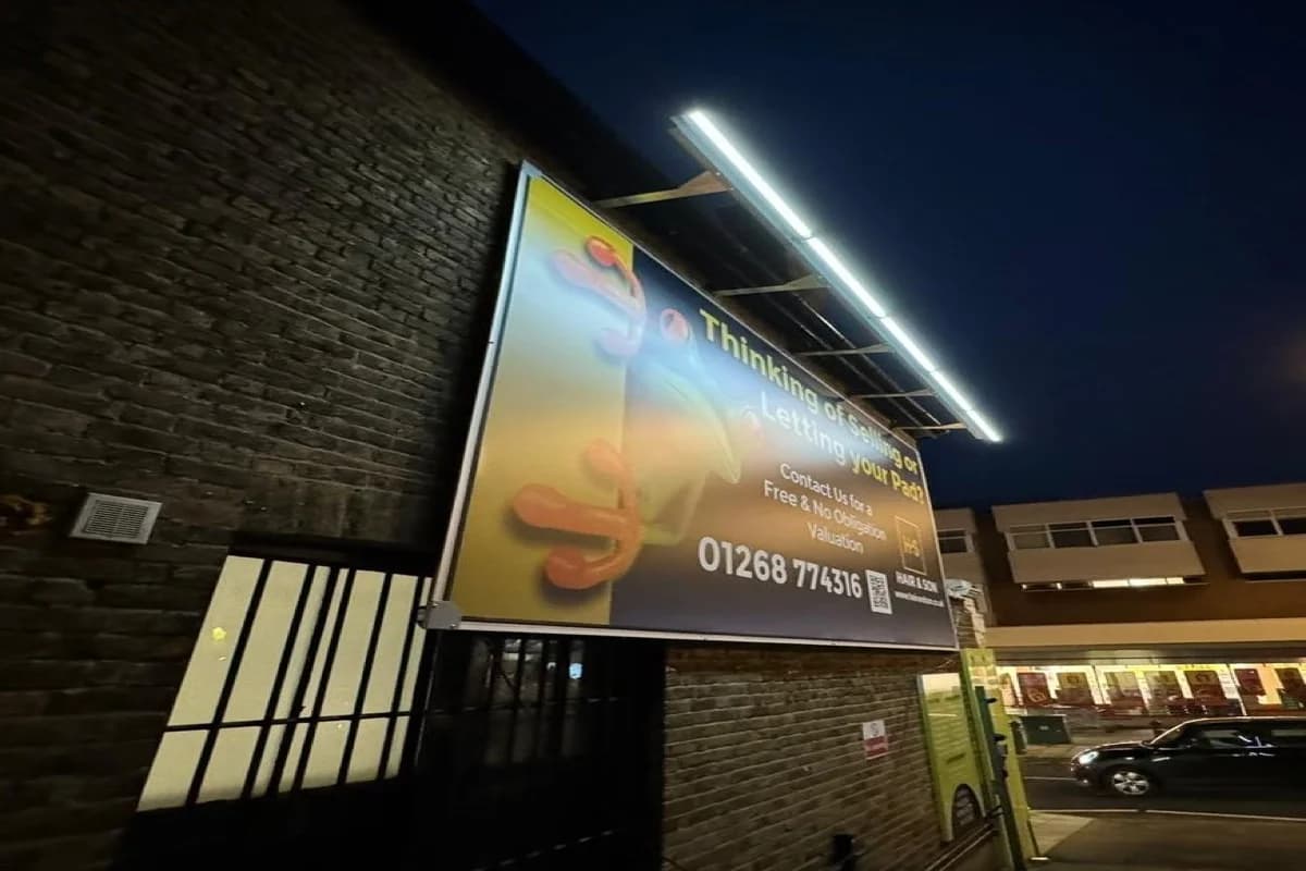 Stretch canvas billboard with overhead solar-powered illumination